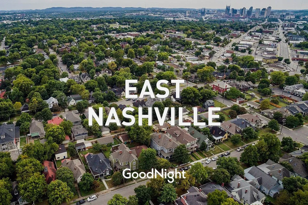 A welcoming streetscape view of a residential Nashville neighborhood with lush greenery and an urban skyline backdrop, suggesting a friendly, walkable, and family-oriented community.