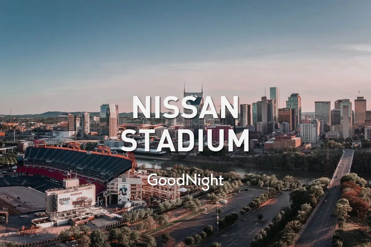 A panoramic city-view featuring Nissan Stadium, the skyline, the river, and intersecting roads. The stadium is a prominent focal point, surrounded by the glow of city lights, showing the venue within close reach of central Nashville attractions.
